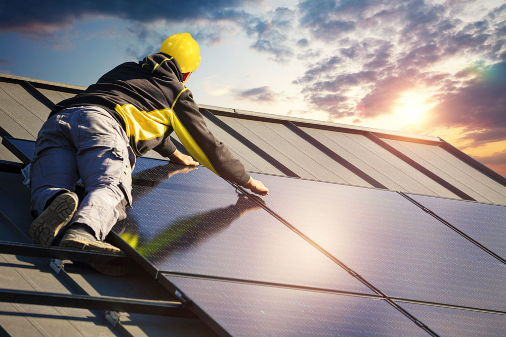 Man som installerar solceller på ett tak