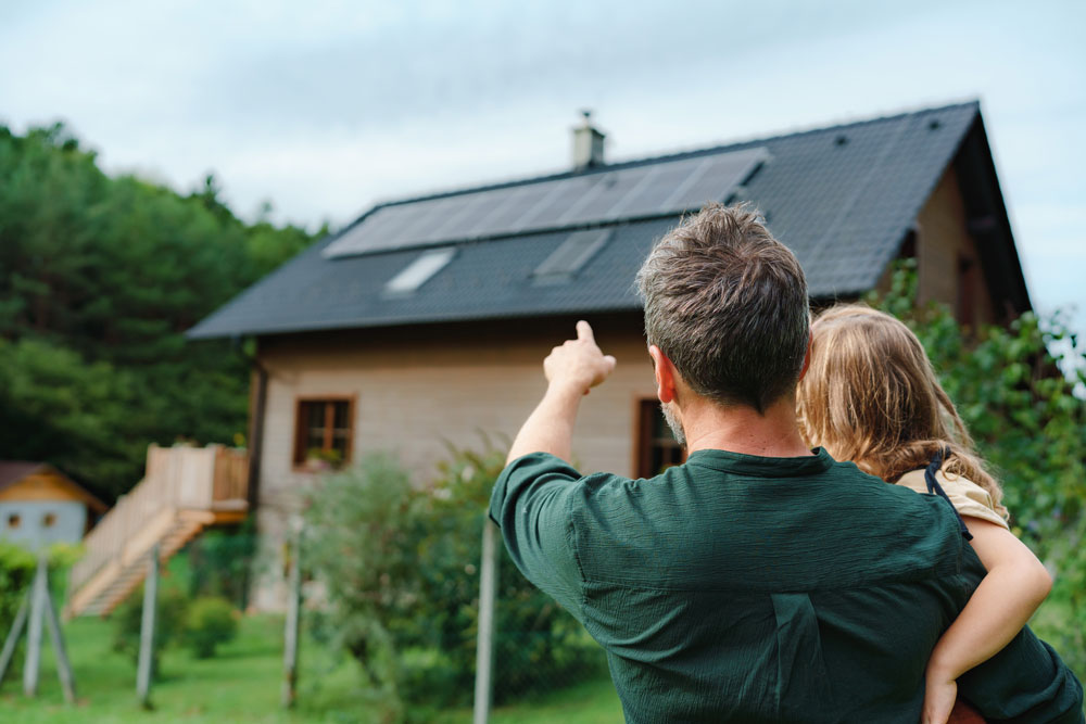 Pappa och dotter som kollar på nyinstallerade solceller på ett villatak